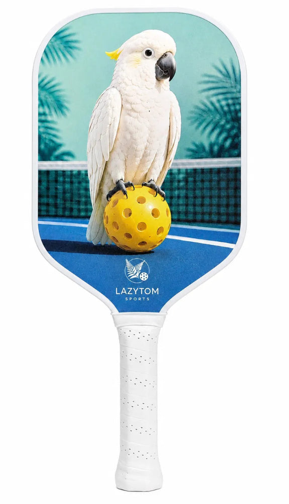 A Lazy Tom Pickleball paddle featuring a printed graphic of a white cockatoo standing on a yellow pickleball on a blue tennis court, with the Lazy Tom Tennis logo near the bottom of the paddle face.