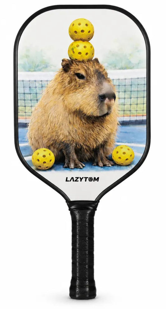 A LazyTown pickleball paddle featuring a printed graphic of a capybara balancing yellow pickleballs on its head, set against a clean white background.